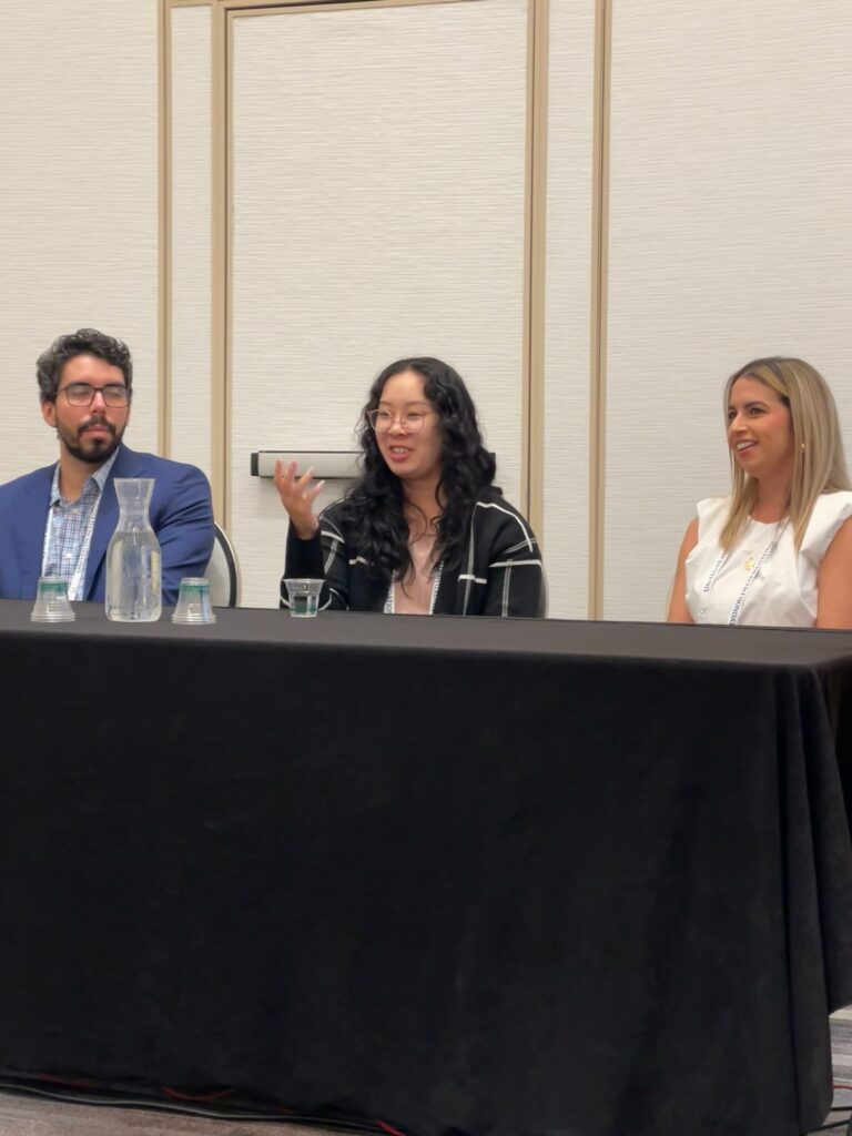 Three individuals are sitting behind a table during a panel discussion