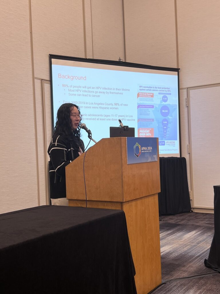 Asian woman standing behind a podium presenting at a conference