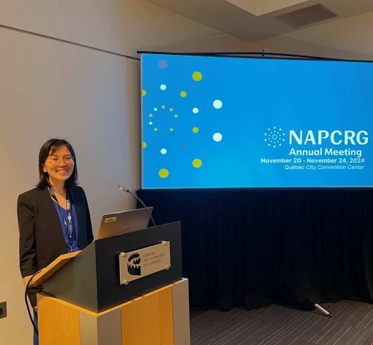 Asian woman standing behind a podium presenting at a conference